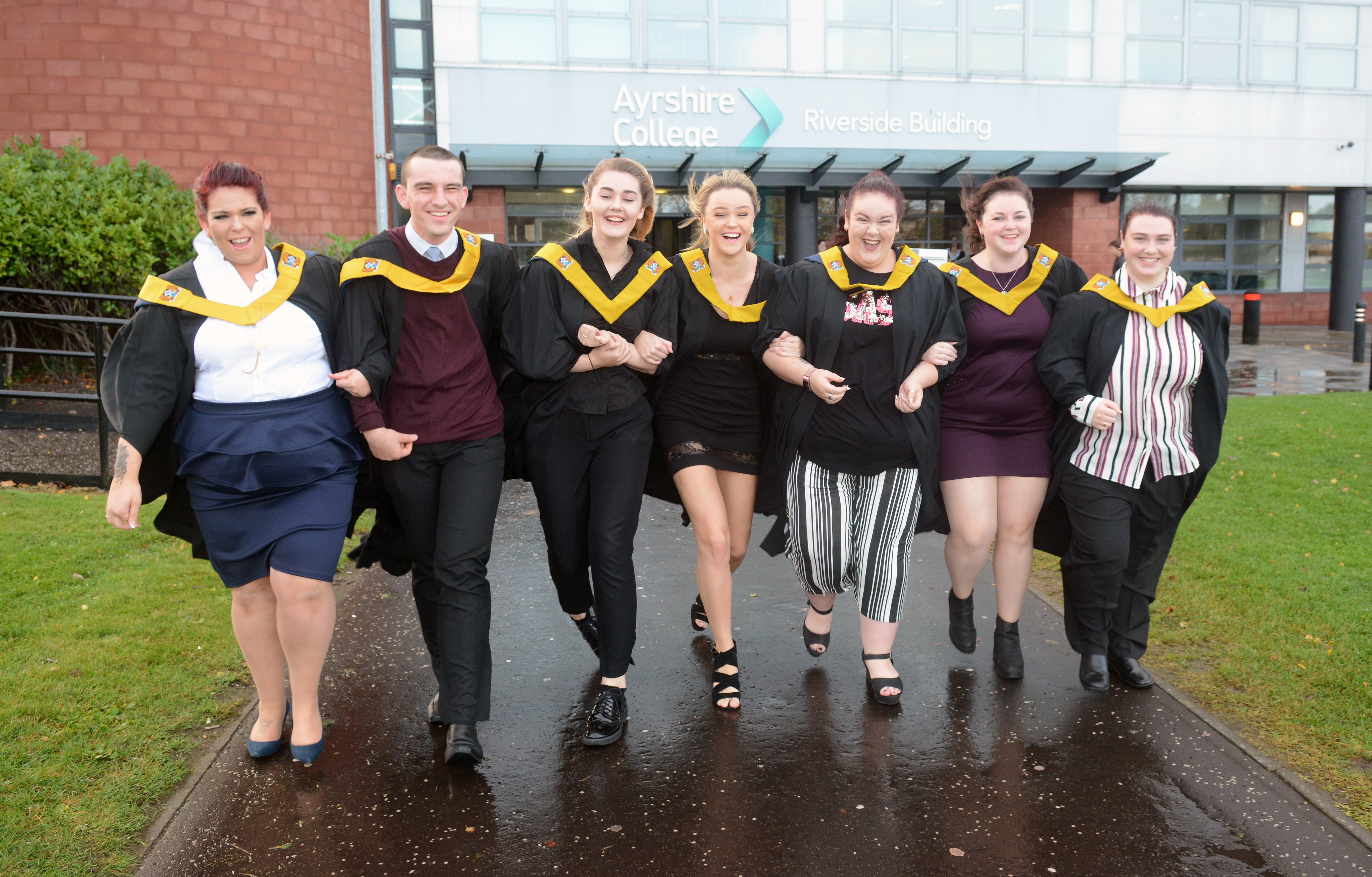 Ayrshire College graduates in gowns linking arms outside the Ayr Campus