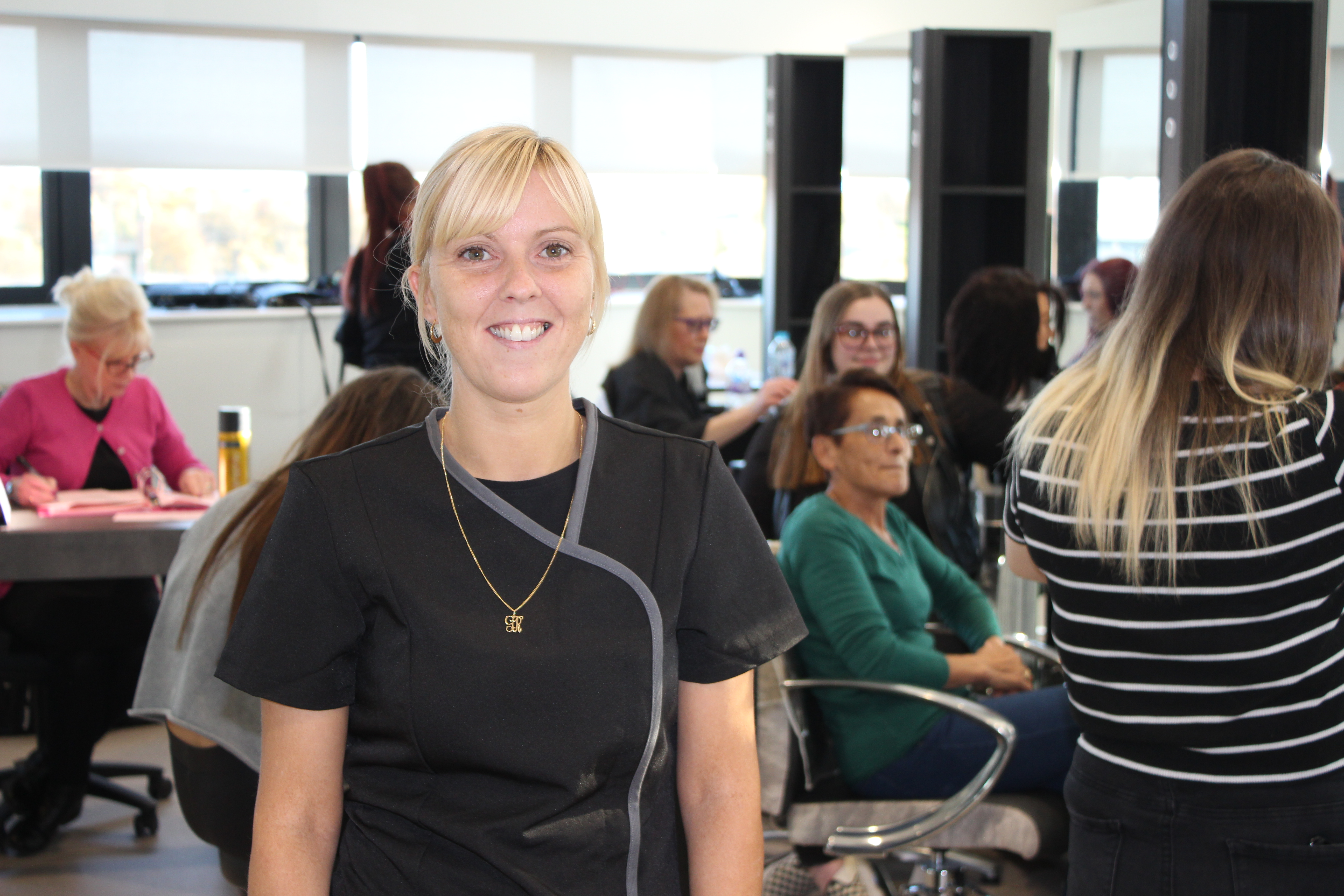 Hairdressing student Gemma in class with classmates and lecturer behind her